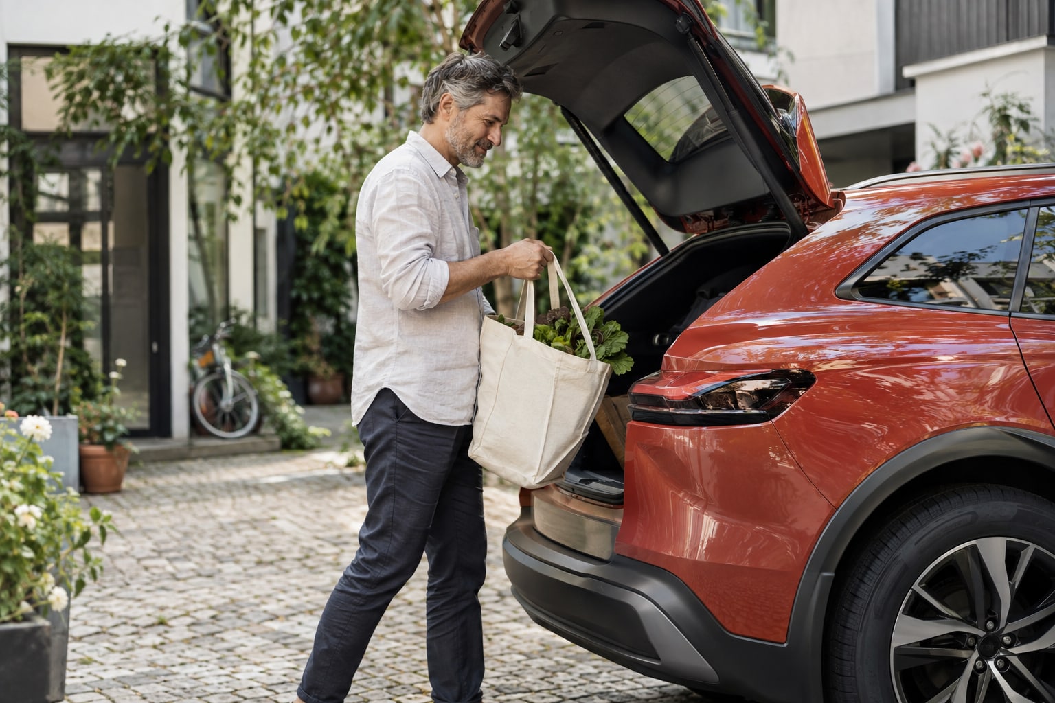 Adcuri Autoversicherung: Vertriebsname und vertraglichen Versicherer auseinanderhalten. Mann verstaut eine helle Tasche im roten SUV vor der Fahrt