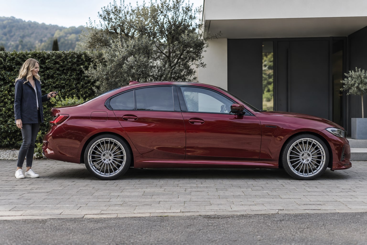 Alpina B3: rote Sportlimousine mit Frau vor einem Wohnhaus