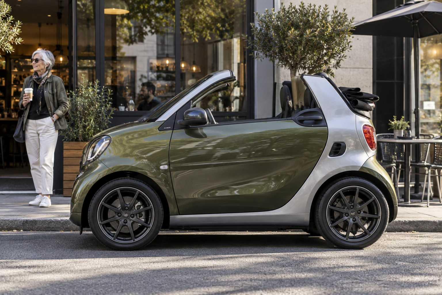 BRABUS Ultimate E Kfz-Versicherung: smart-basierte Elektro-Karosserie, Cabrio-Dach und Individualausstattung getrennt prüfen. Grünes offenes Elektro-Stadtauto mit Frau vor einem Café: Brabus Ultimate E Kfz-Versicherung