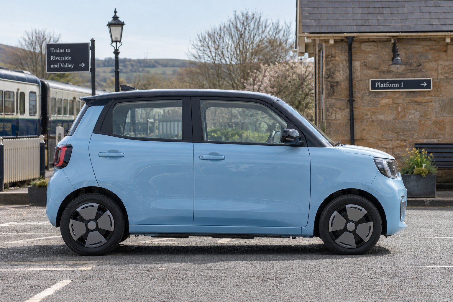 Dacia Spring – Kleines Elektroauto und Zweitwagen Hellblauer Dacia Spring im Seitenprofil an einem Bahnhof