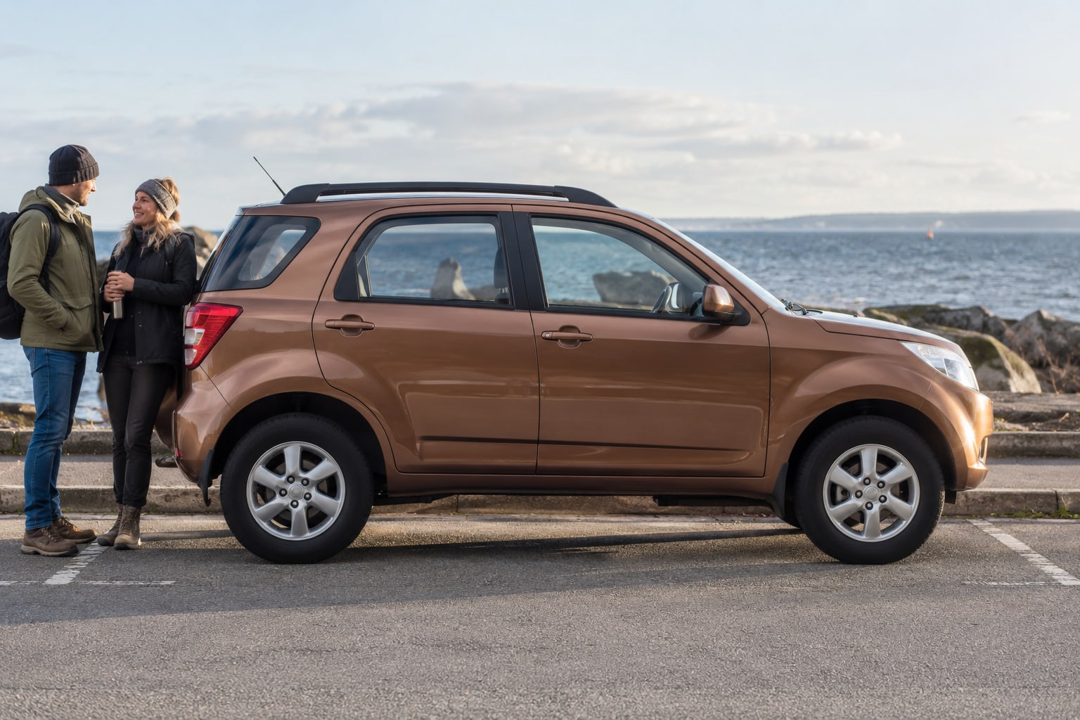 Daihatsu Terios Kfz-Versicherung: SUV-Ausführung und Reiseausstattung vor dem Vergleich richtig zuordnen. Brauner kompakter SUV am See: Daihatsu Terios Kfz-Versicherung nach Ausführung