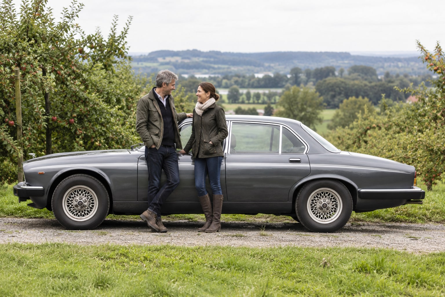 Daimler Double Six Kfz-Versicherung: V12-Ausführung und Restaurierungszustand für den passenden Wertschutz festhalten. Graue historische Limousine in einer Garteneinfahrt: Daimler Double Six Kfz-Versicherung