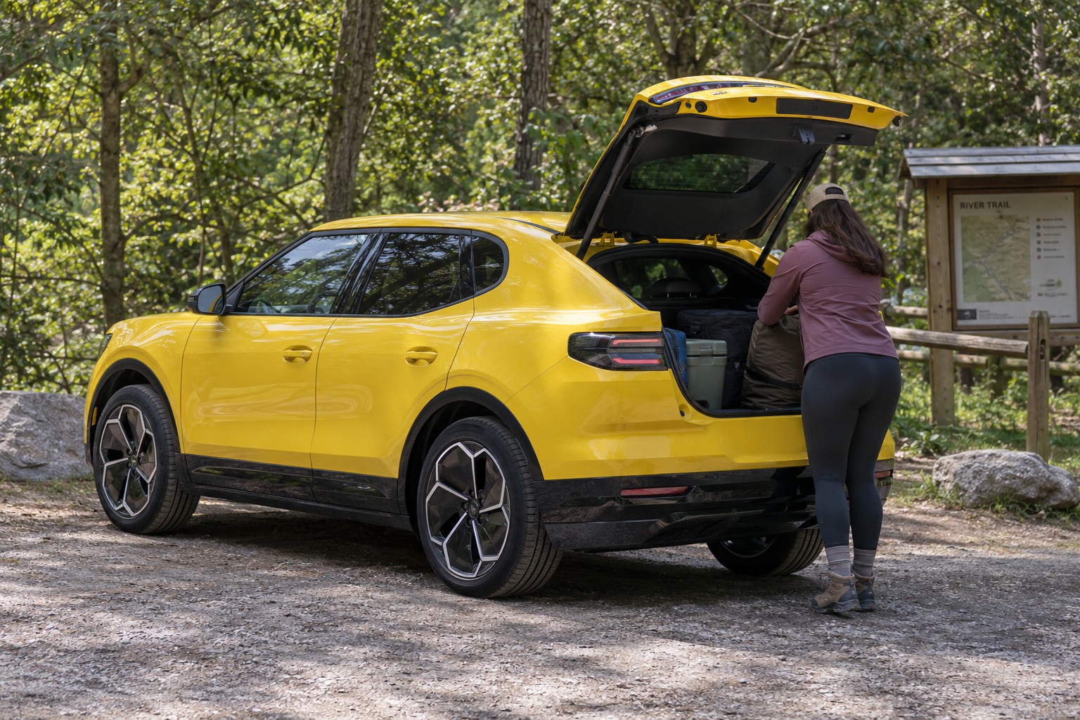 Ford Capri – Neues Elektro-SUV oder klassisches Coupé Frau lädt Gepäck in einen gelben elektrischen Ford Capri am Waldrand