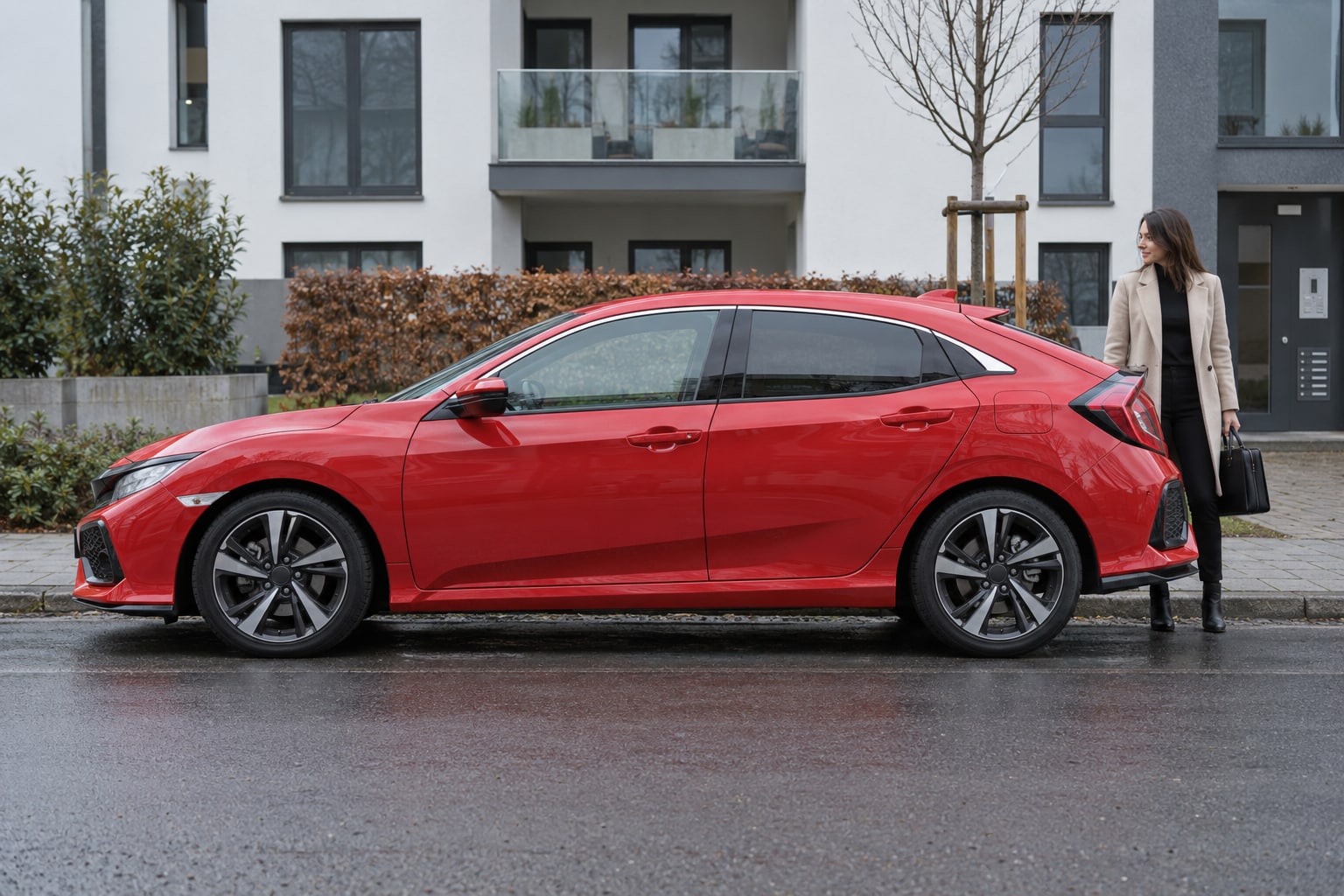 Honda Kfz-Versicherung: Vollhybrid, Plug-in und ältere Generationen vor dem Tarifvergleich richtig unterscheiden. Roter Kompakt-Fastback vor einem Wohngebäude: Honda Autoversicherung nach Fahrzeugausführung
