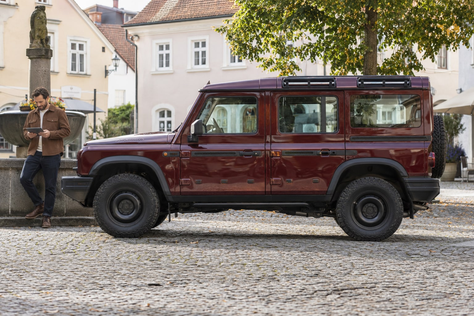 Ineos Kfz-Versicherung: Pkw, Utility Wagon und Pick-up anhand von Aufbau und Zulassung eindeutig erfassen. Roter kantiger Geländewagen auf einem Stadtplatz: Ineos Kfz-Schutz nach Zulassung und Nutzung