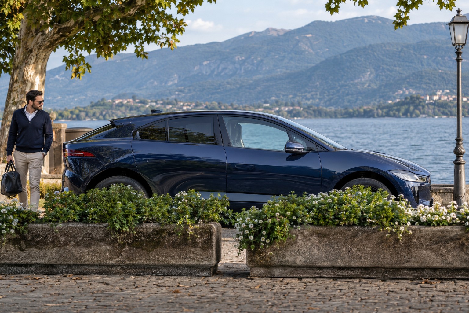 Jaguar I-Pace – Fahrzeug und Versicherung Jaguar I-Pace im Seitenprofil; dunkelblauer Wagen mit natürlichen Vordergrundpflanzen
