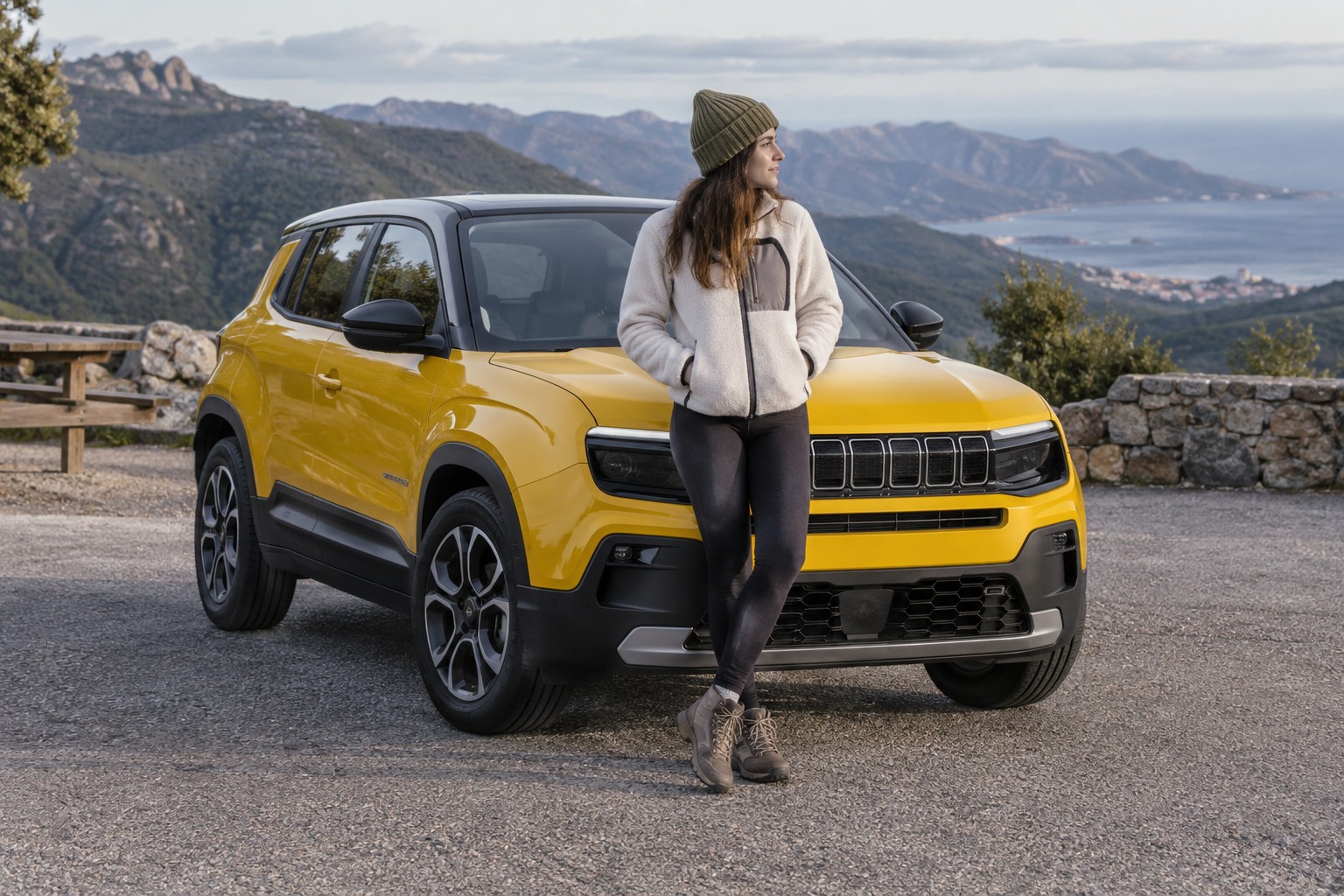 Avenger Elektro, Hybrid und 4xe brauchen ihre eigene Versicherungszuordnung. Frau vor einem gelben kompakten SUV an einem Aussichtspunkt