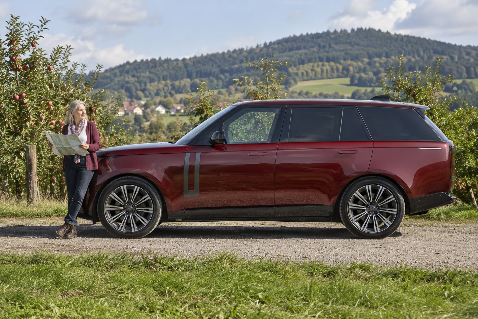 Range Rover Autoversicherung: eigenständige Baureihe, Ausführung und hochwertigen Kaskobedarf prüfen. Bordeauxroter SUV vor einem Berghaus: Land Rover Range Rover Autoversicherung