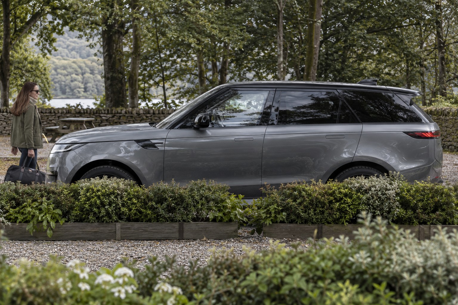 Land Rover Range Rover Sport im Seitenprofil; grauer Wagen mit natürlichen Vordergrundpflanzen