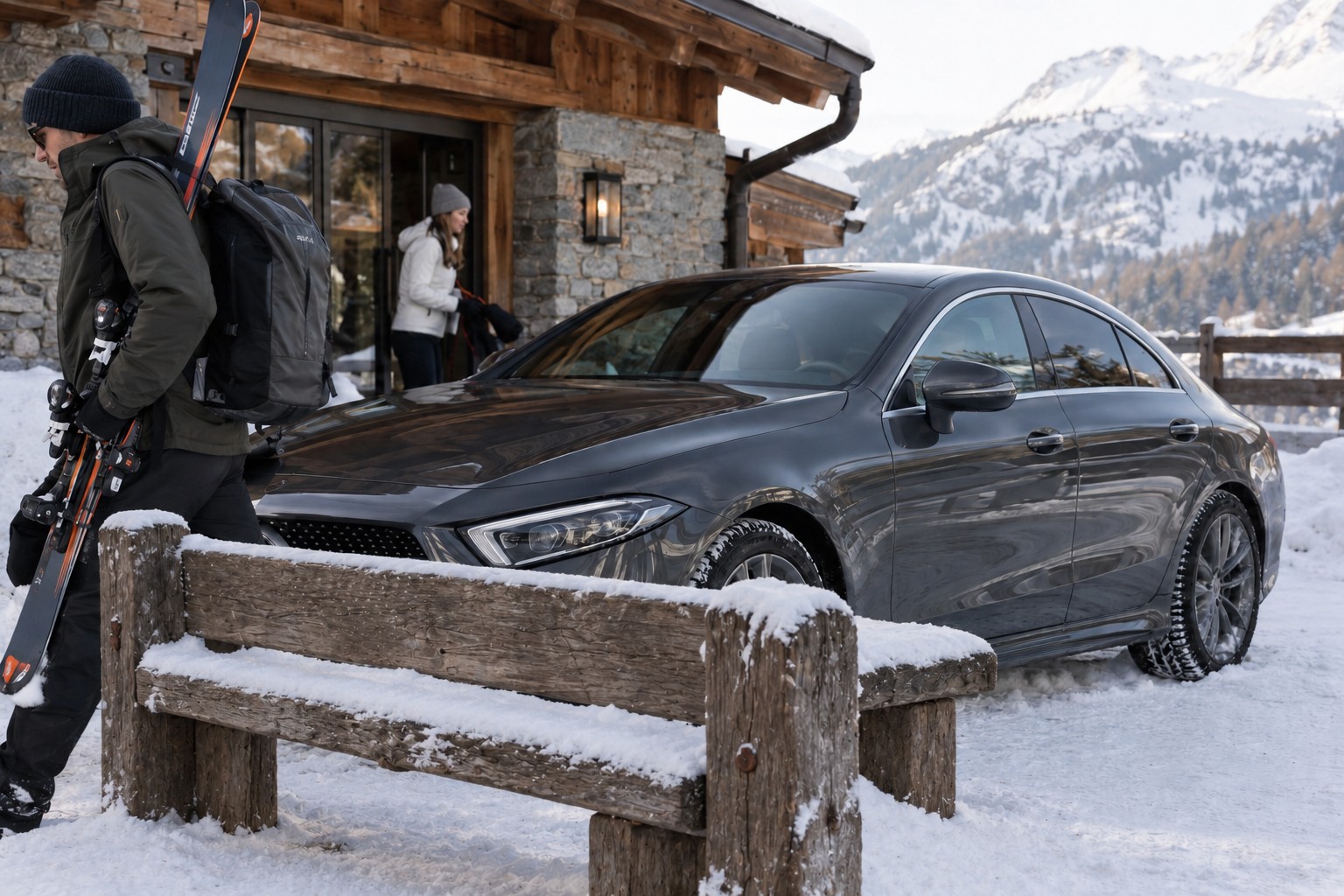 Dunkelgrauer Mercedes-Benz CLS vor einem verschneiten Gasthaus mit Skiern