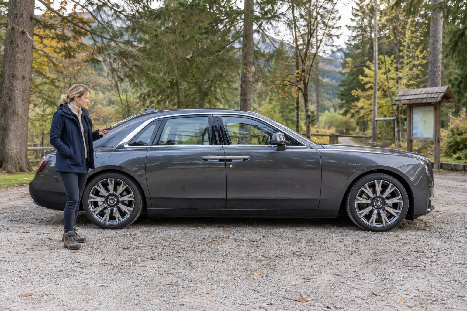 Rolls-Royce Autoversicherung: Graue große Limousine mit Frau an einer Wiese