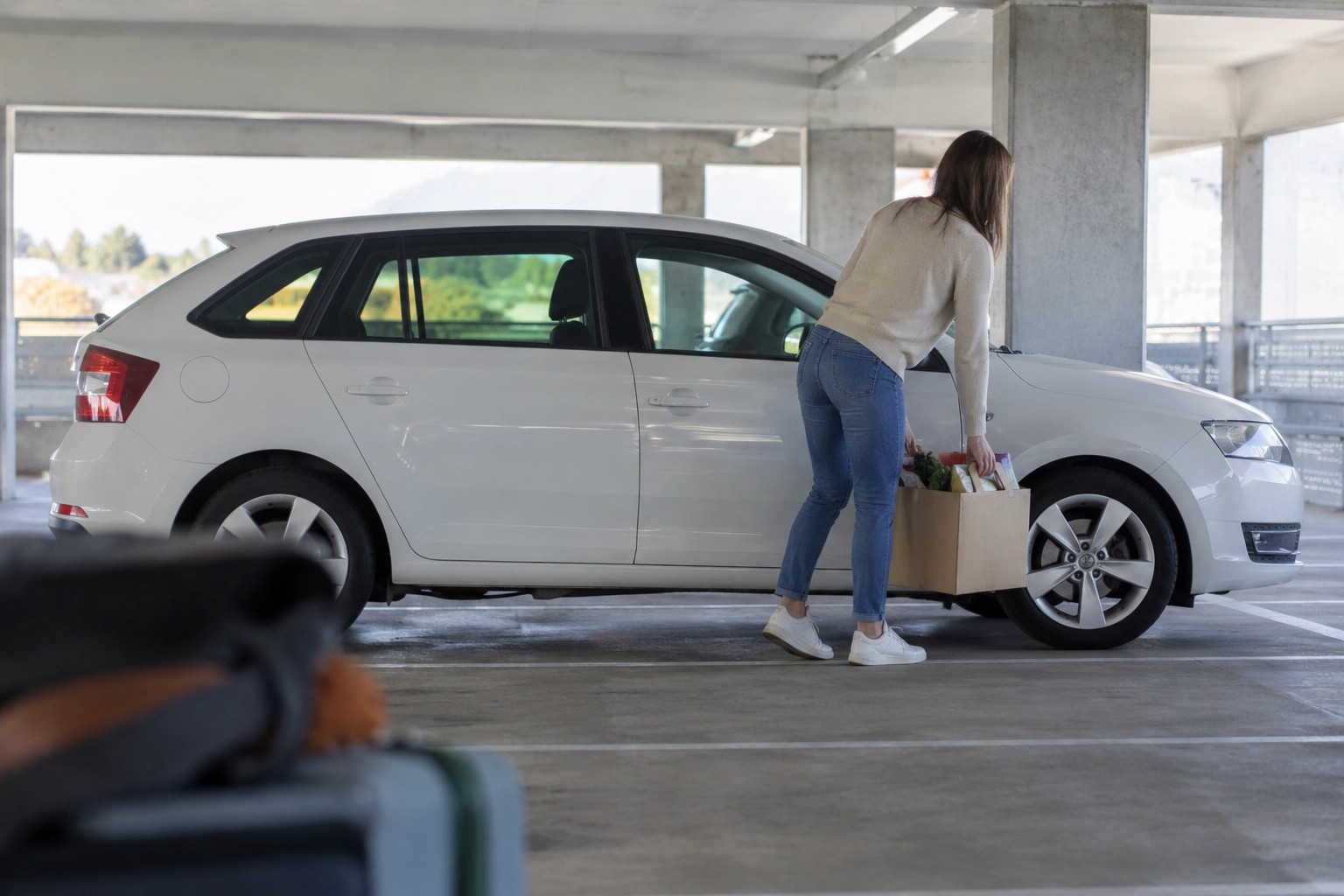 Škoda Rapid Versicherung: Spaceback und Liftback Weißer Škoda Rapid in einem hellen Parkhaus neben Einkaufskartons