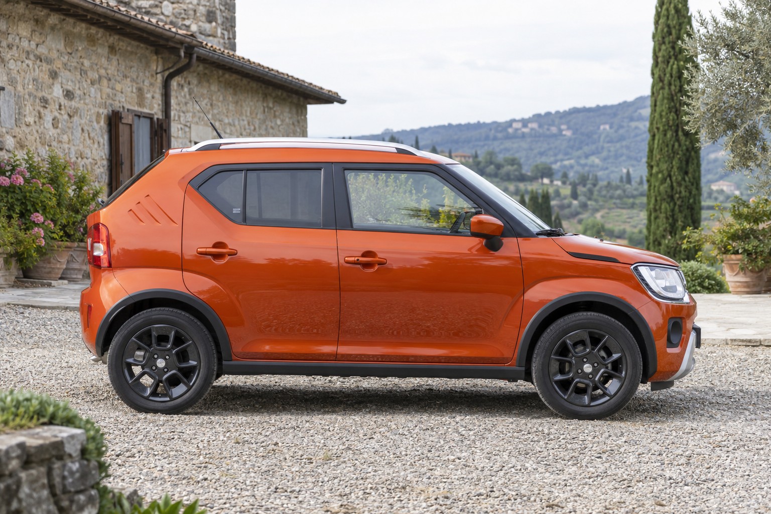 Orangefarbener Suzuki Ignis im Seitenprofil an einem Landgasthof