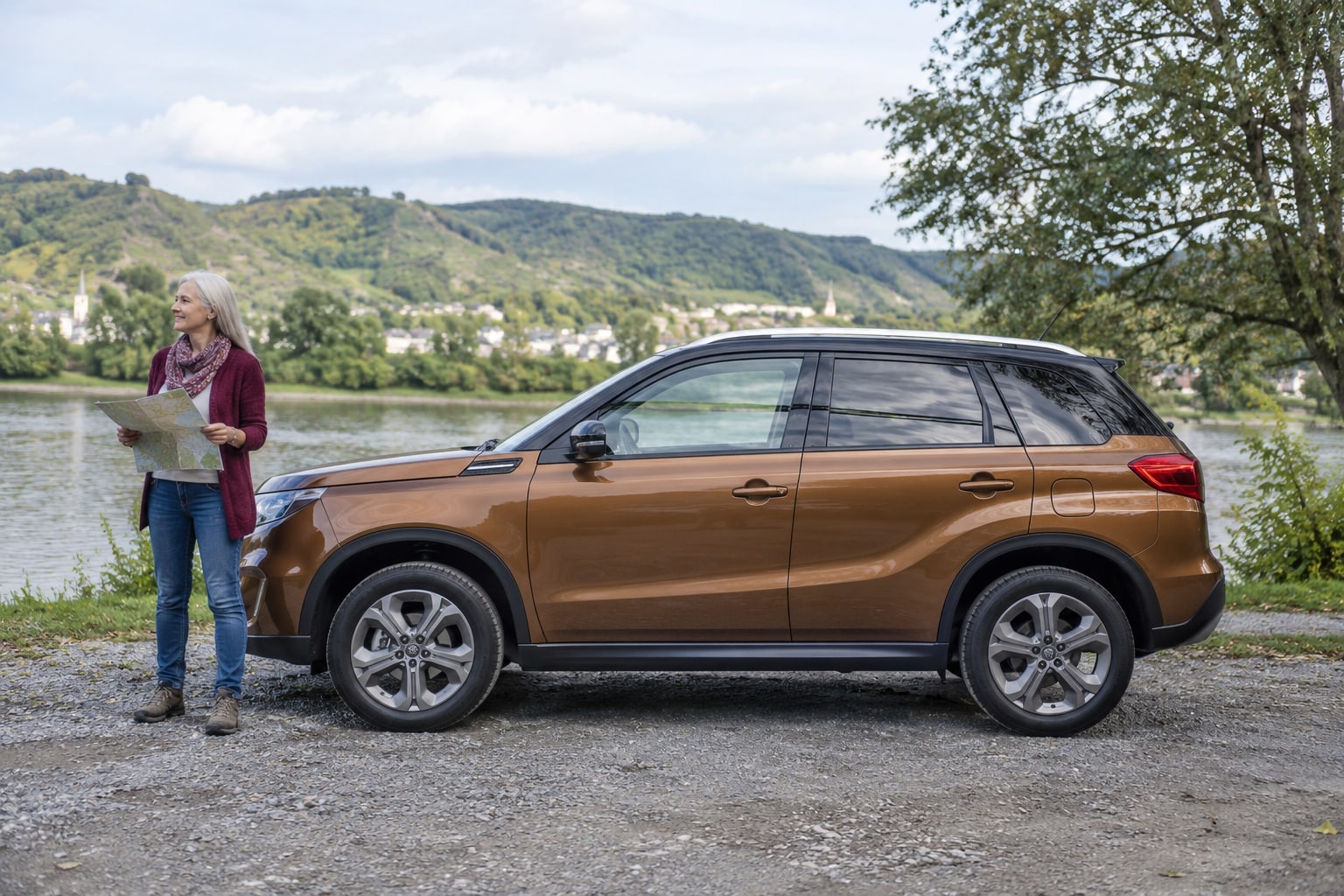 Suzuki Vitara Kfz-Versicherung: Hybridversion und eigenständigen e VITARA mit passenden Fahrzeugdaten unterscheiden. Bronzefarbener SUV mit Frau an einem Feldweg: Suzuki Vitara Autoversicherung