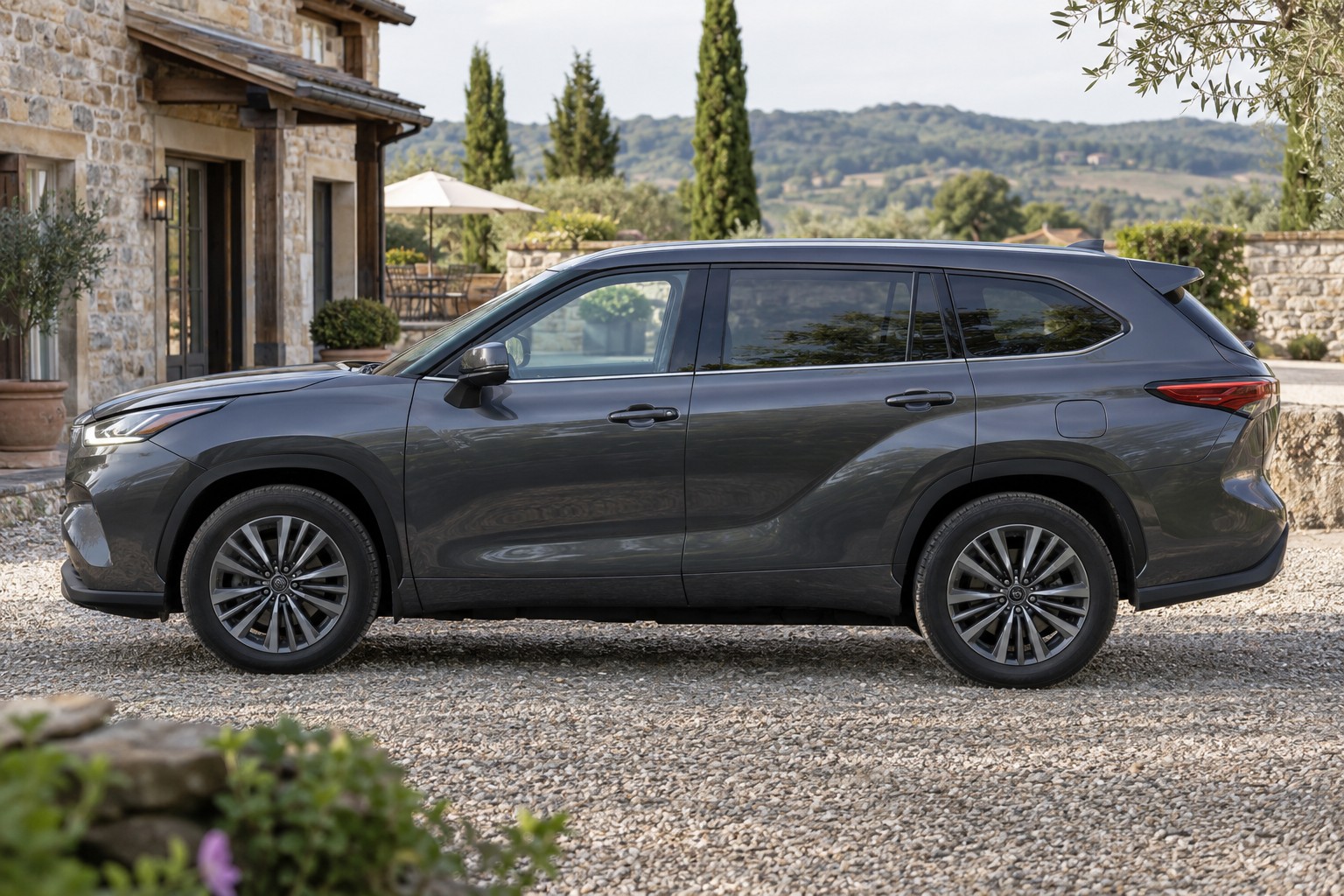 Dunkelgrauer Toyota Highlander im Seitenprofil vor einem Landgasthof