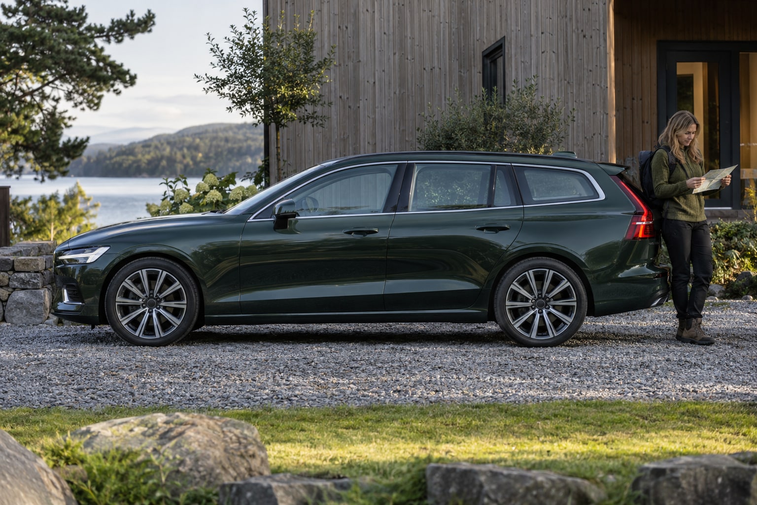 Volvo Autoversicherung: Grüner Kombi mit Frau vor einem modernen Haus