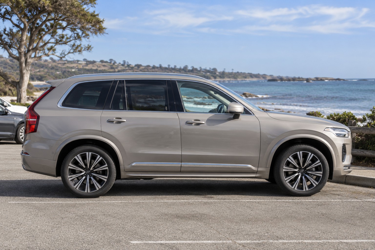 Volvo XC90 – Familien-SUV, T8 und sieben Sitze Sandgrauer Volvo XC90 im Seitenprofil auf einem Küstenparkplatz