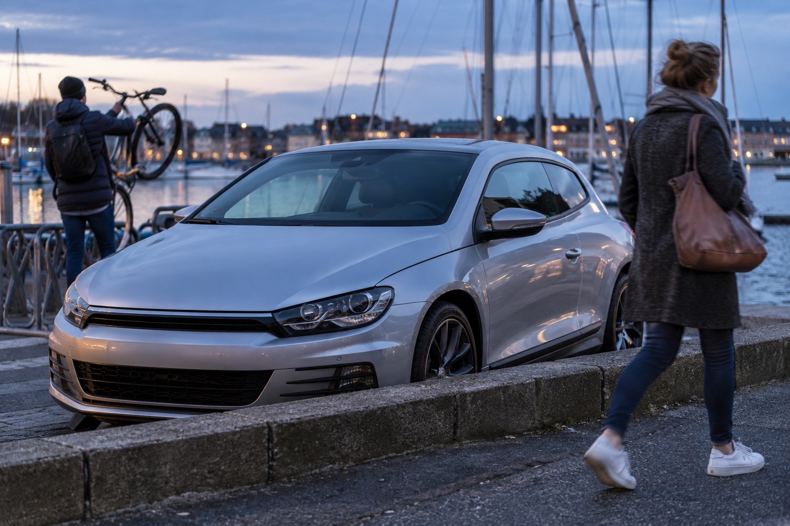 VW Scirocco: Scirocco TSI, TDI und R sollten anhand ihrer Motor- und Typkennungen auseinandergehalten werden. Silberner VW Scirocco an einem Hafen mit Fahrrad und Gepäck