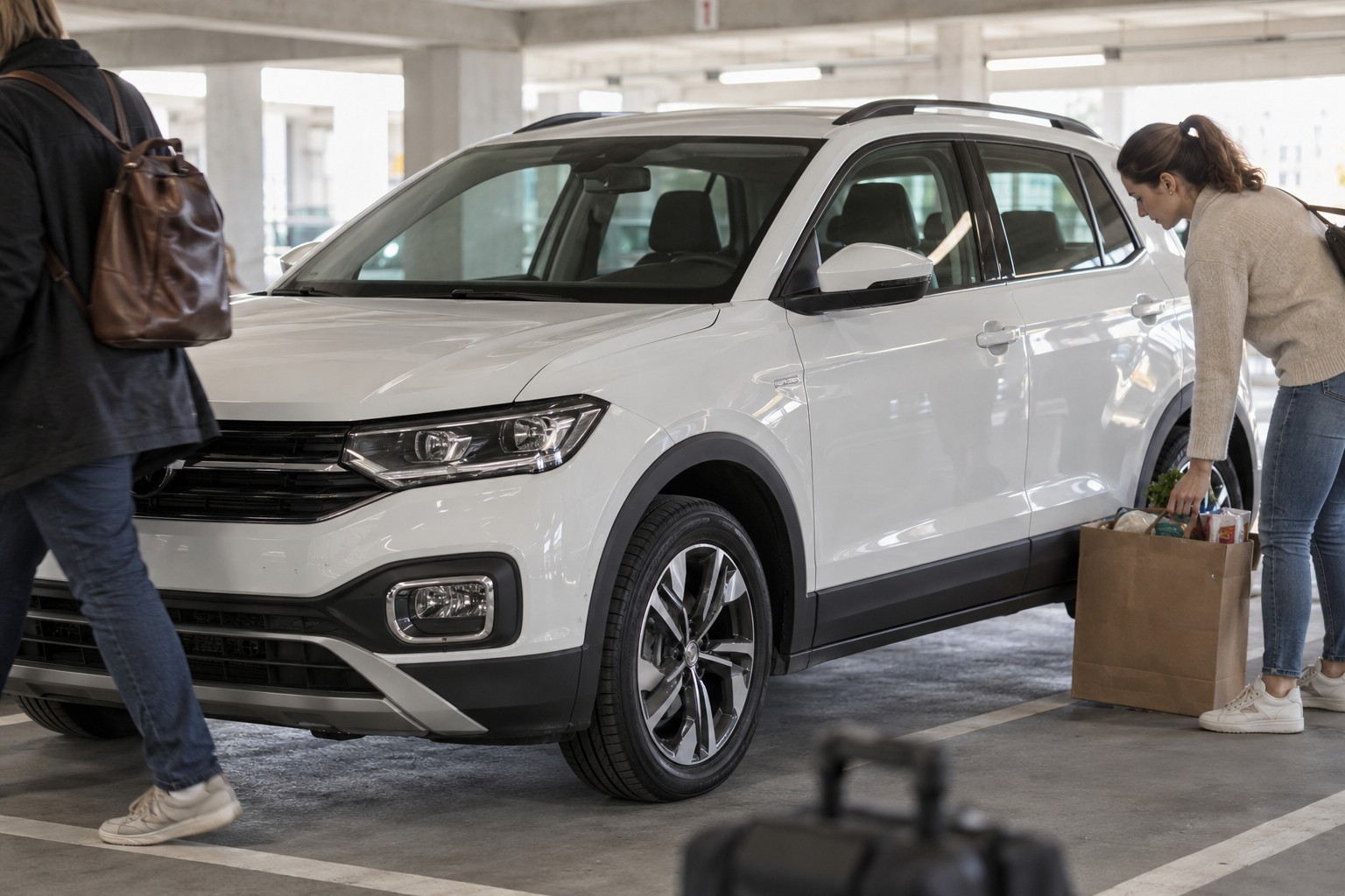 Weißer VW T-CROSS in einem hellen Parkhaus neben Einkaufskartons